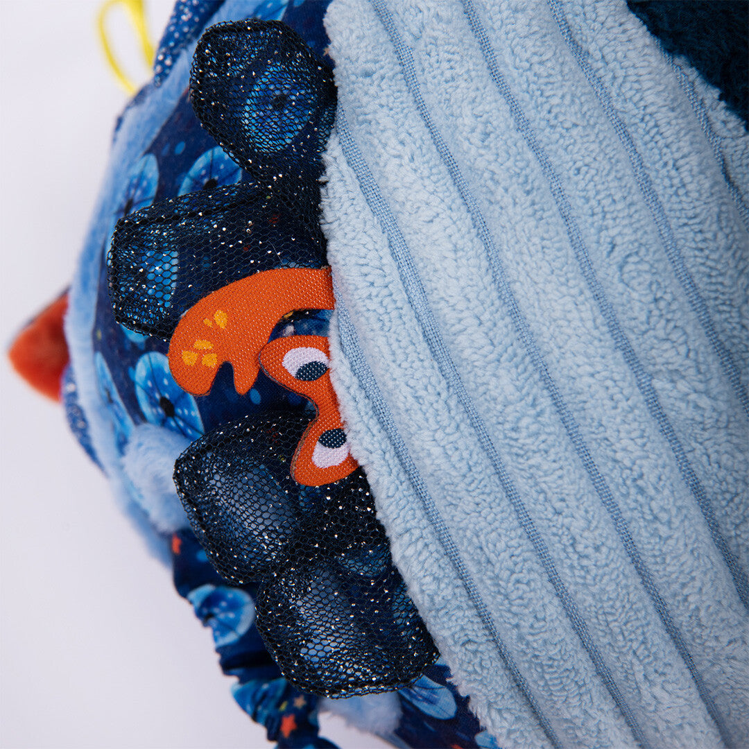 Detail van de Moulin Roty activiteitenbal met een oranje visje dat uit de blauwe stof steekt.
