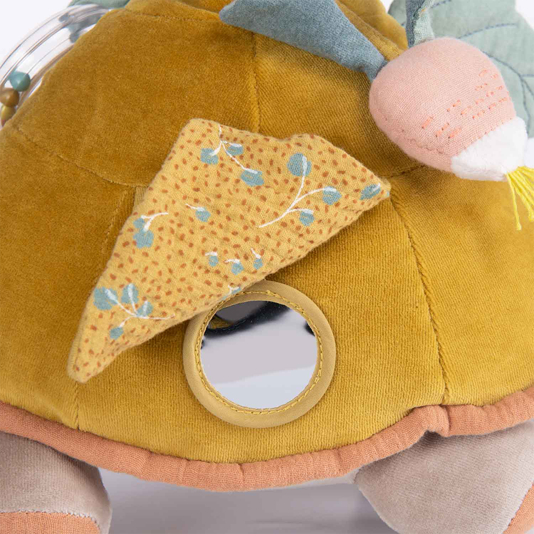 Detail van de ronde spiegel en een driehoekig stoffen flapje op de gele schild van de activiteitsschildpad.