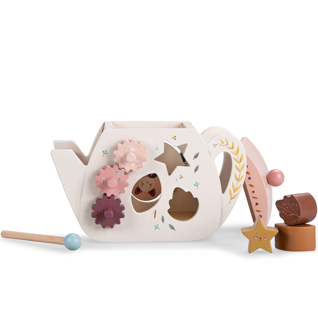 Moulin Roty houten activiteitenkubus theepot met de deksel en vormpjes ernaast, en een hamer met bal.