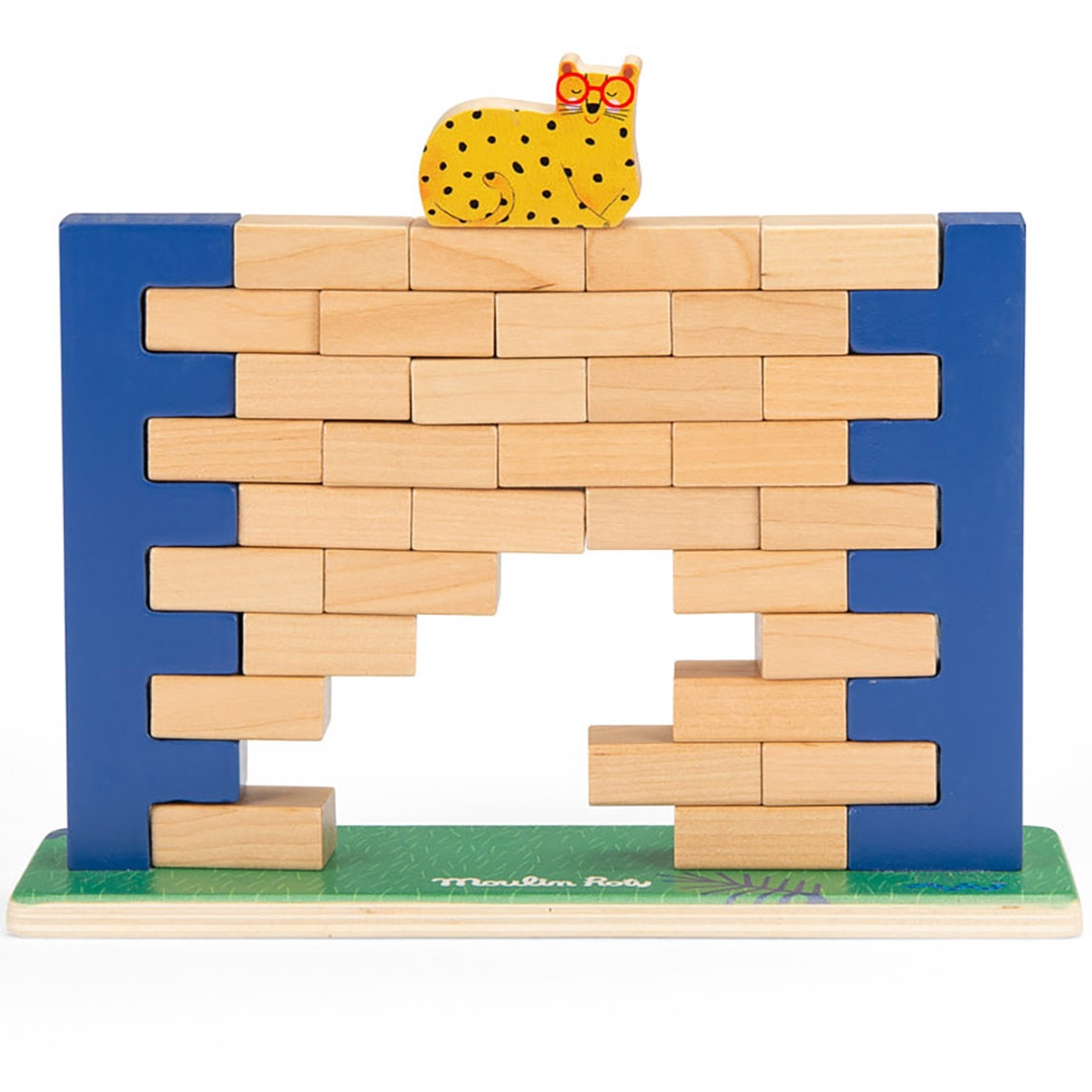 Moulin Roty balansspel met een wiebelende wand van houten bakstenen en een gele kat bovenop, van voren gezien.
