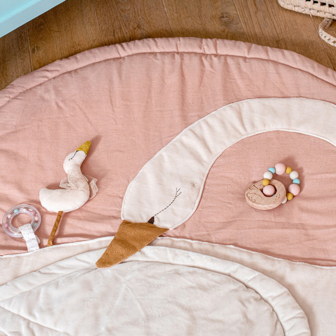 Moulin Roty houten bijtring rammelaar met zwaan op een roze zwanen speelkleed.