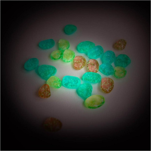 Veelkleurige plastic glow-in-the-dark meteorieten liggen lichtgevend in het donker.