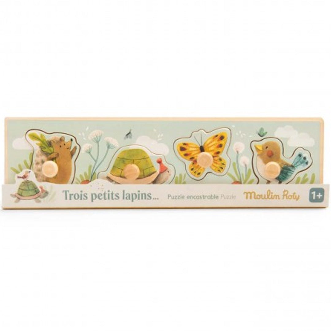 Verpakking van de Moulin Roty houten knoppuzzel voor peuters met dierenfiguren en de tekst 'Trois petits lapins'.