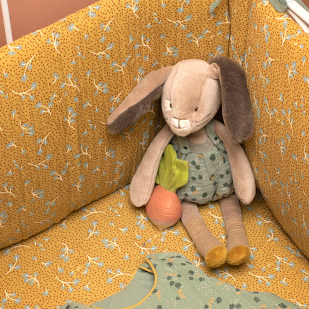 Knuffelkonijn met wortel zittend in een geel wiegje.
