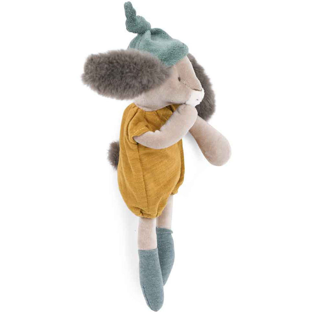 Moulin Roty knuffelkonijn met okergele romper en groen mutsje, schuin van de zijkant gezien.