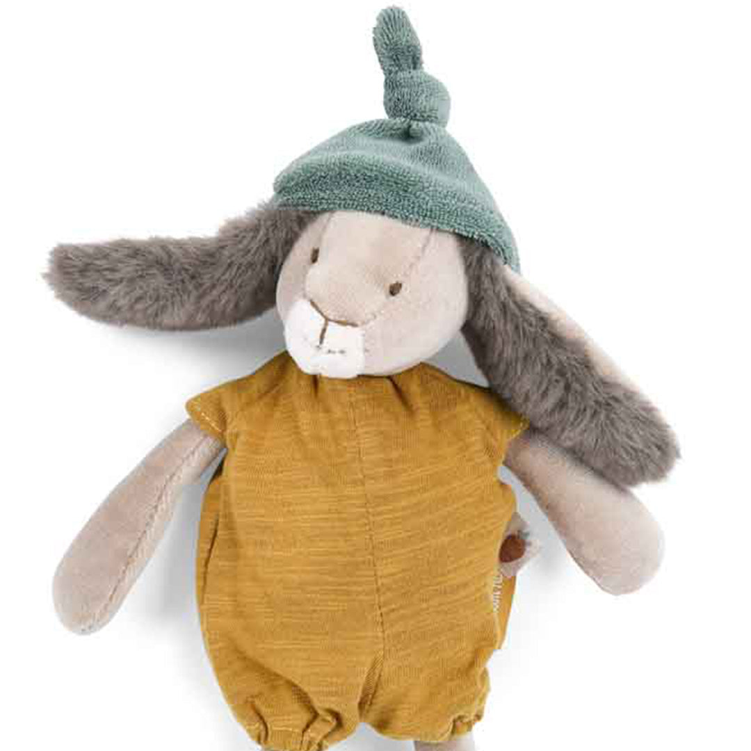 Detailopname van het Moulin Roty knuffelkonijn met okergele romper en groen mutsje.