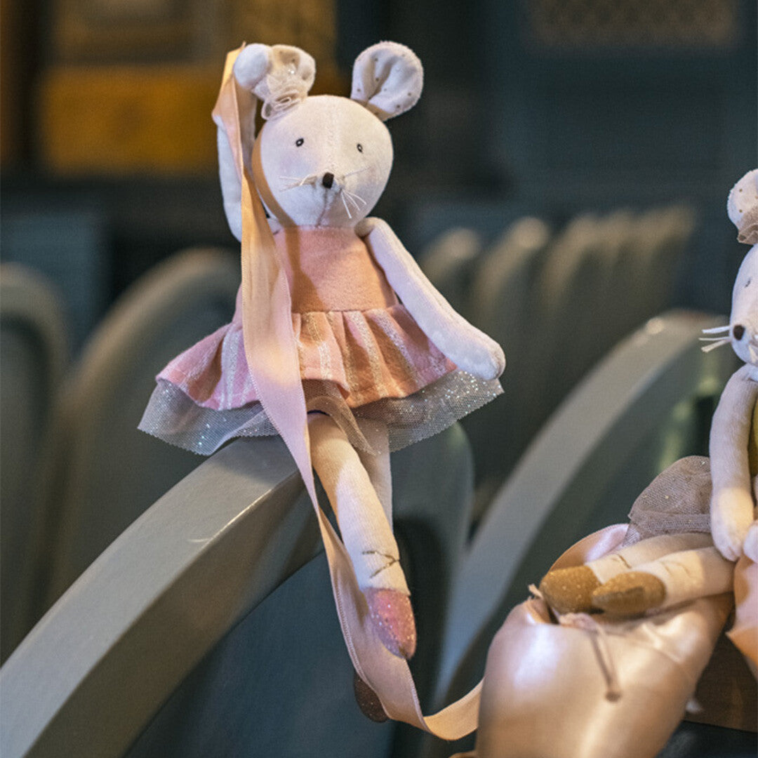 Moulin Roty knuffelmuis ballerina zit op een leuning en houdt een roze lint vast.