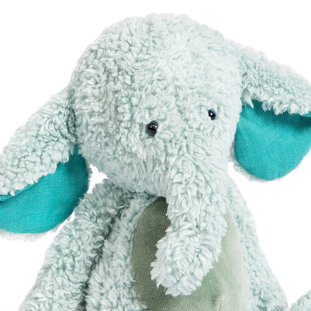 Detailopname van de kop en bovenkant van een Moulin Roty pluchen knuffelolifant in lichtblauw met teal oren.