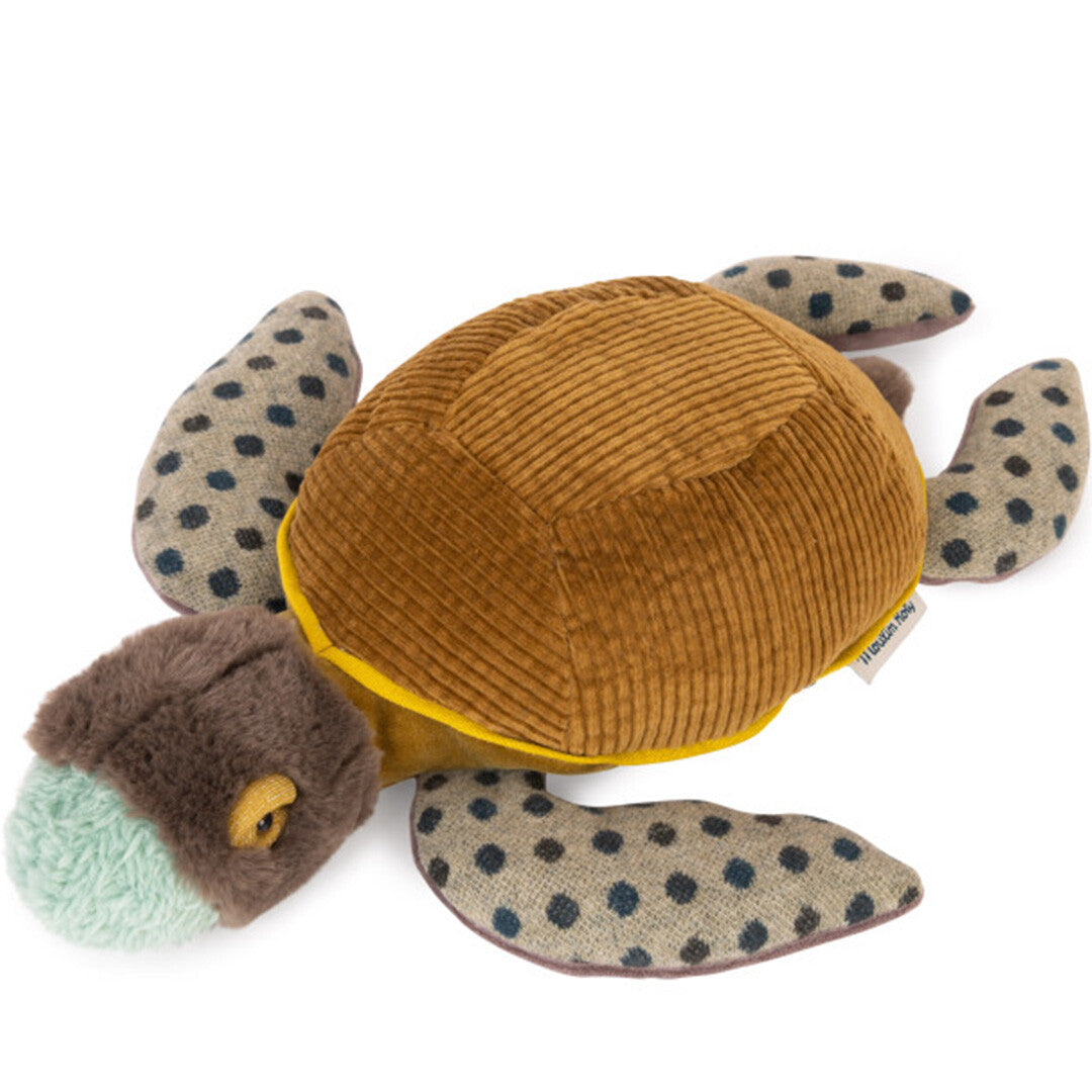 Moulin Roty pluchen schildpad met bruin corduroy schild en gespikkelde flippers, van bovenaf gefotografeerd.