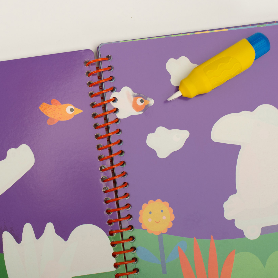 Detail van een open magisch schilderboek met paarse pagina's, witte vormen van dieren en wolken, en een gele waterpen.