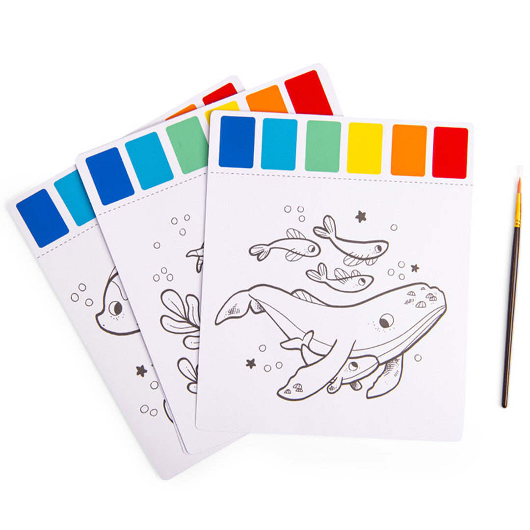 Drie magische schilderpagina's met een walvis en vissen, elk met een ingebouwd kleurpalet en een kwastje ernaast.