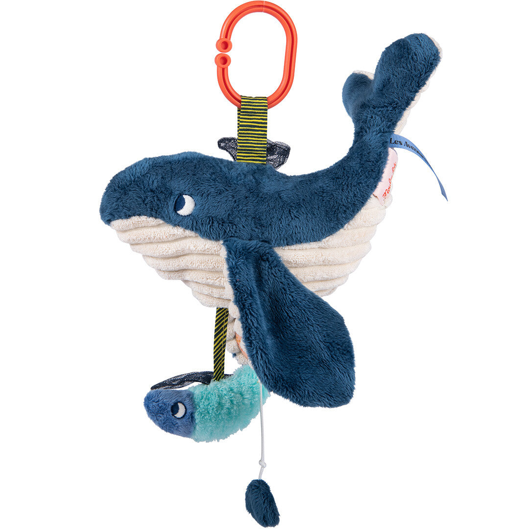 Moulin Roty babyspeelgoed muziekdoosje in de vorm van een blauwe walvis, hangend aan een oranje clip.