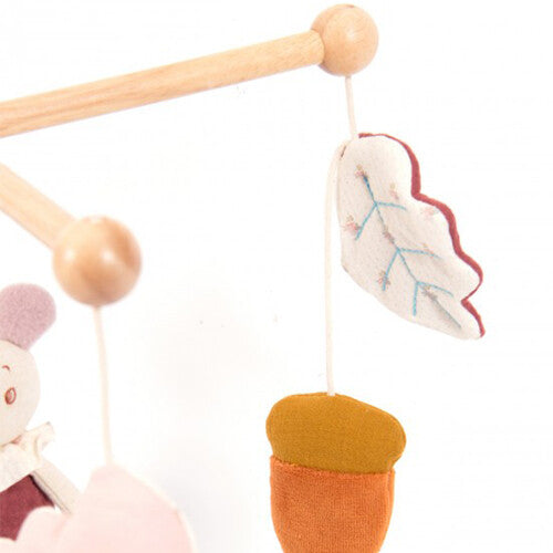Detail van de Moulin Roty babymobiel met een houten arm, een wit stoffen blad en een oranje stoffen eikel.