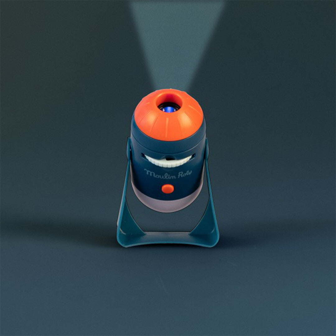 De Moulin Roty projector met een glimlachend gezicht, die een lichtstraal omhoog projecteert.