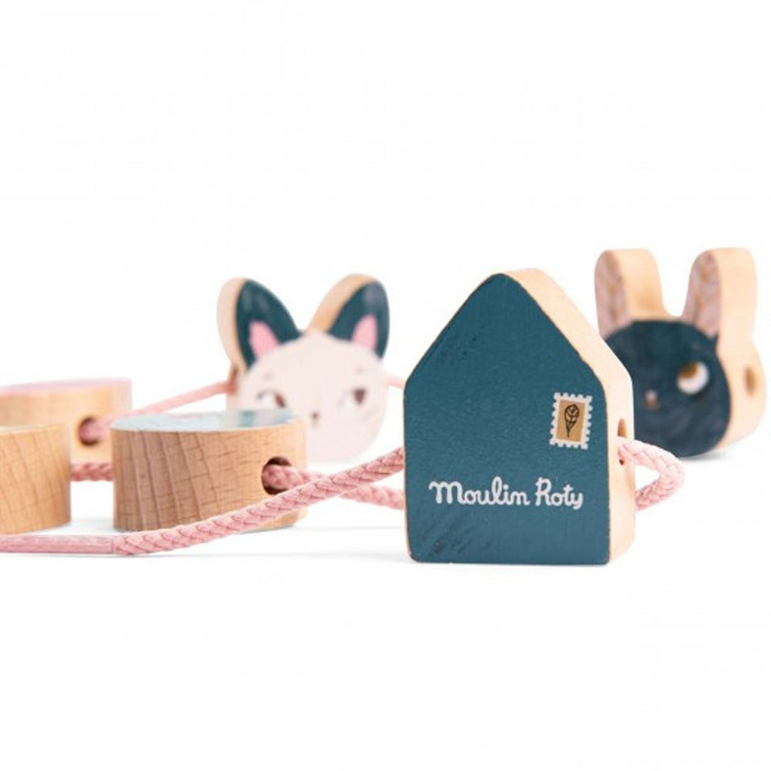 Detail van Moulin Roty houten rijgkralen voor peuters, met een huisje en een konijnenhoofd aan een roze koord.