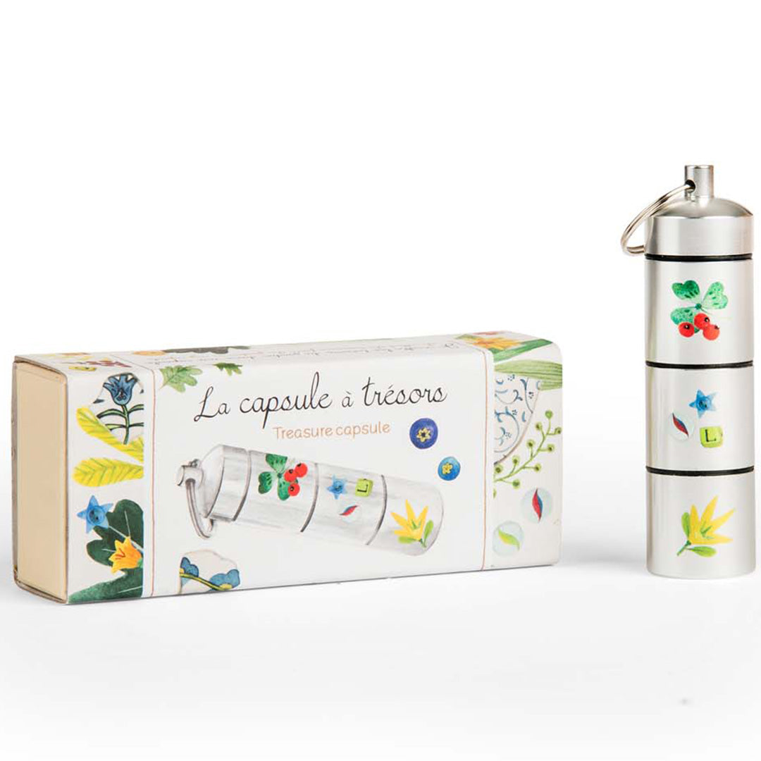De Moulin Roty schatcapsule met bloemen- en bladerpatronen staat naast de bijpassende verpakking.