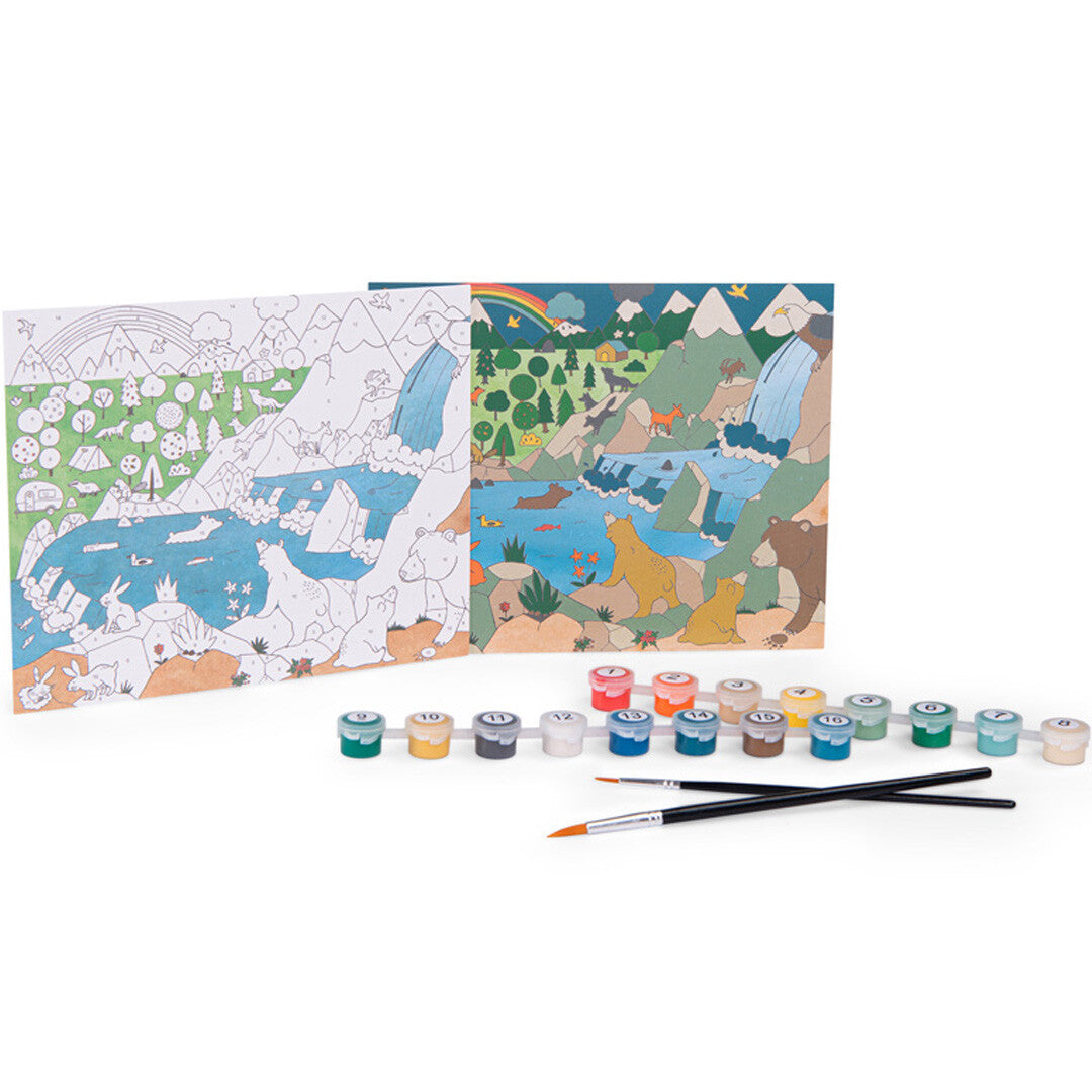 Een verf-op-nummerset met twee vellen papier van een natuurlandschap met dieren, potjes verf en kwasten.