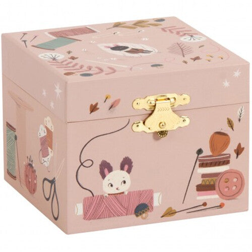 Gesloten roze Moulin Roty muziekdoosje met gouden sluiting, versierd met naaiwerkthema.