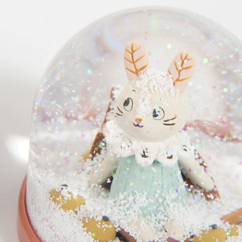 Detail van een sneeuwbol met een konijnfiguur en witte sneeuw op de bodem.