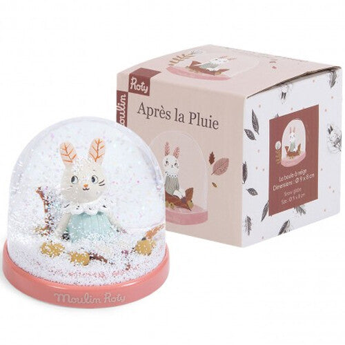 Moulin Roty sneeuwbol met konijnfiguur naast de verpakking met de tekst 'Après la Pluie'.