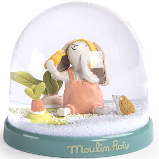 Moulin Roty sneeuwbol met een konijntje in oranje tuinbroek, een vogel, een egel en een wortel, met glitter op de bodem.