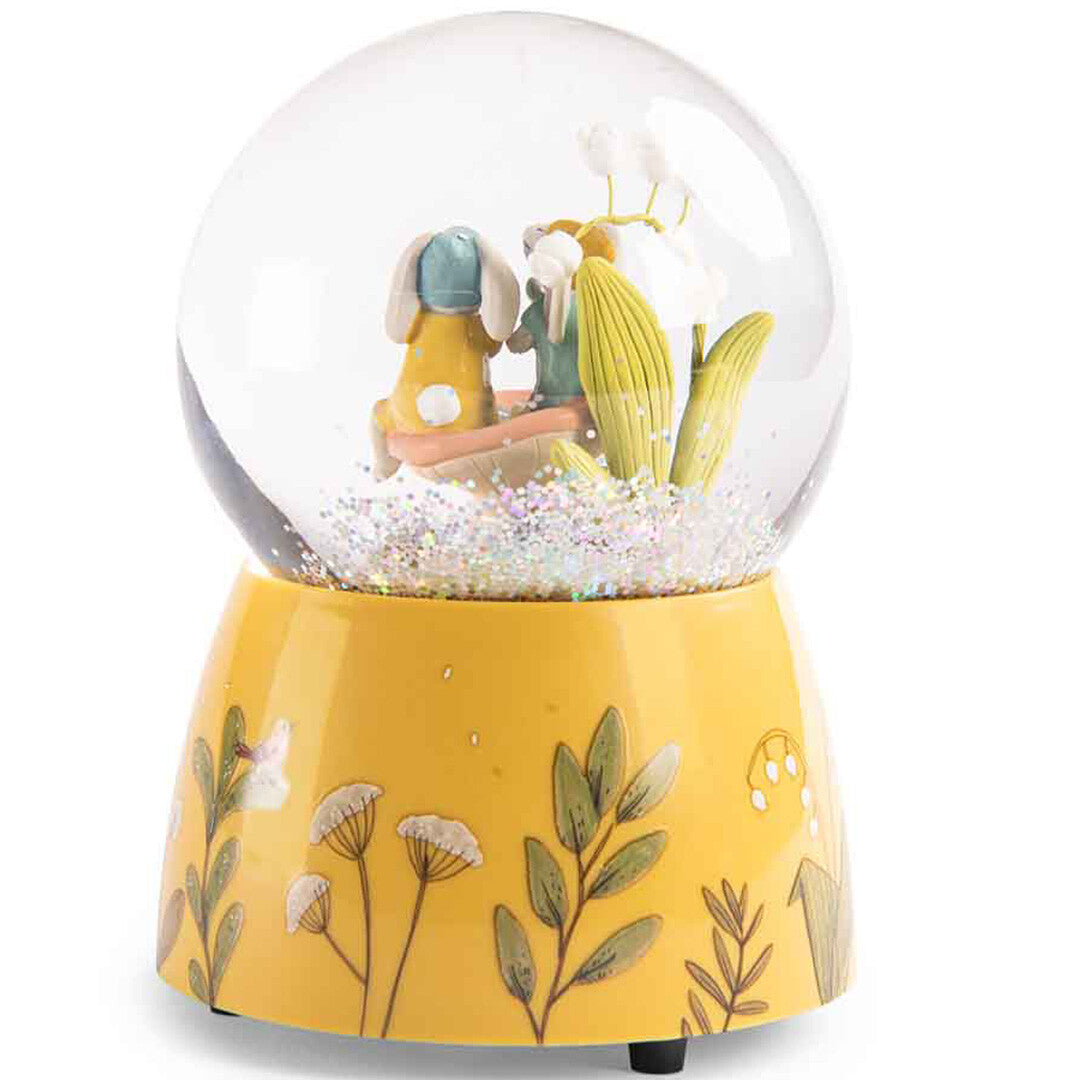 Achterkant van de Moulin Roty sneeuwbol met een gele voet met bloemmotieven en de rug van de konijntjes.