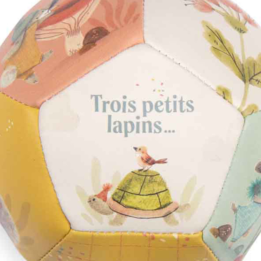 Detail van de babyspeelbal met een schildpad, een vogel en de tekst 'Trois petits lapins...'.