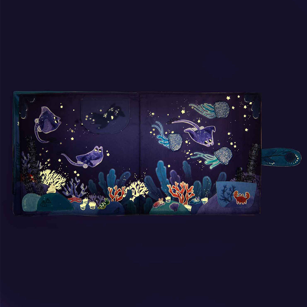 Open stoffen babyboekje met een glow-in-the-dark onderwaterwereld met roggen en kwallen.