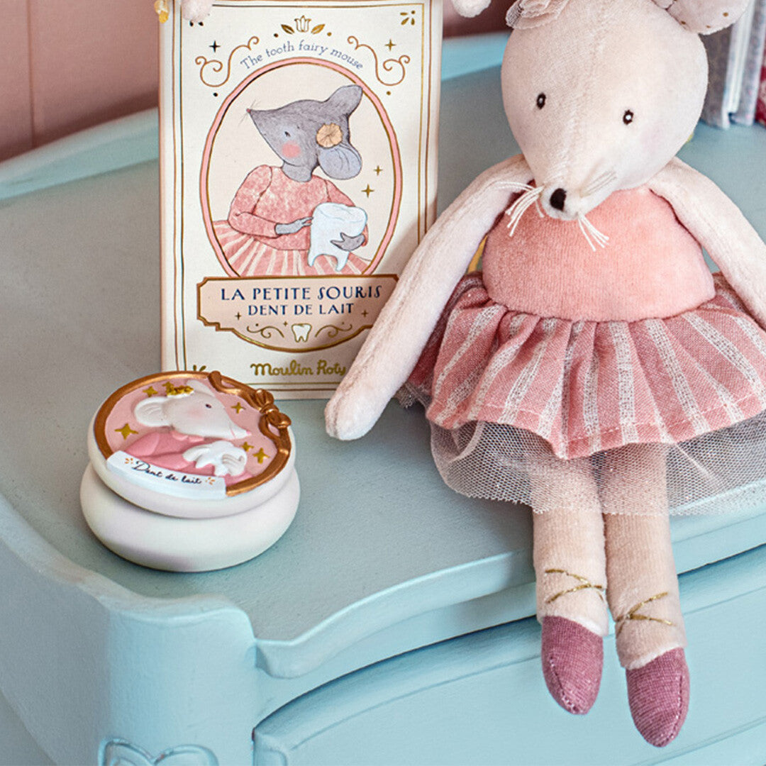 Moulin Roty tandendoosje op een blauwe ladekast, naast een knuffelmuis en een boekje over de tandenfee.