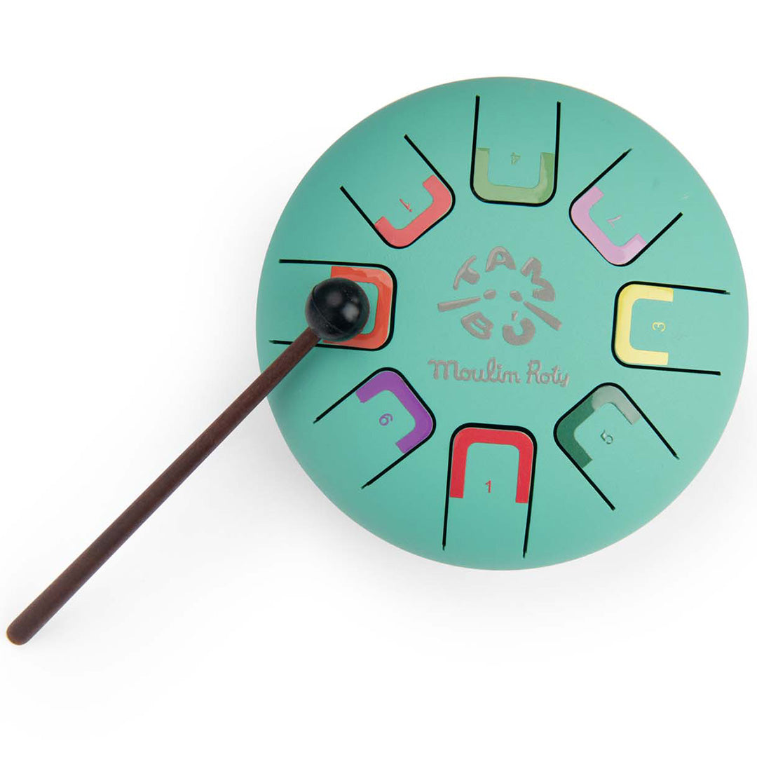 Moulin Roty Tambu tongtrommel, een groen metalen muziekinstrument met gekleurde genummerde tongen en een drumstick.