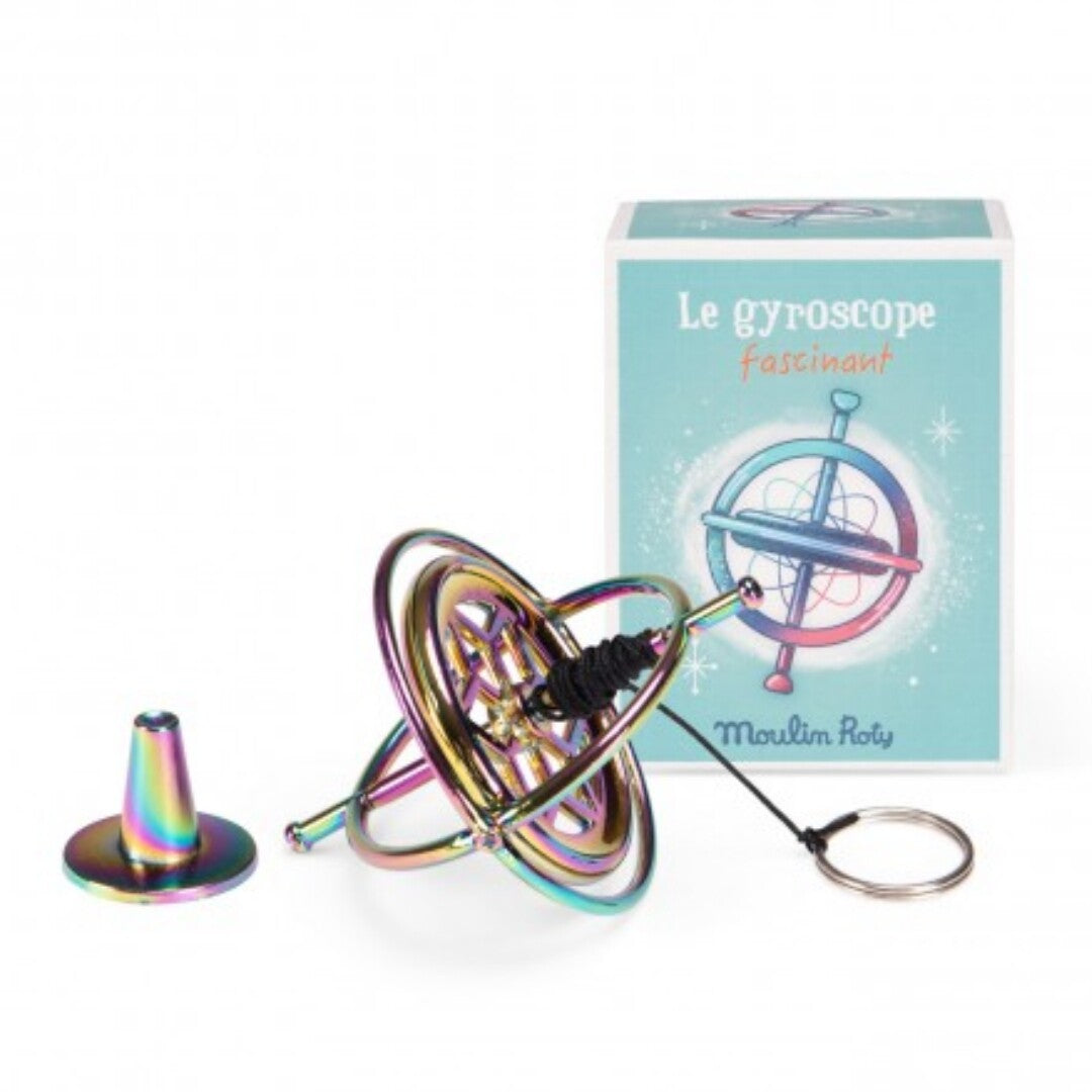 Moulin Roty regenboogkleurige gyroscoop met opgewonden touwtje op standaard, naast de verpakking.