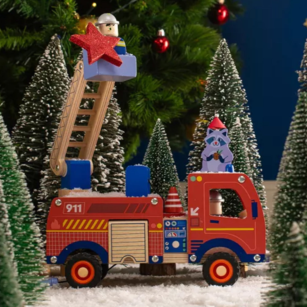 Moulin Roty houten brandweerwagen met brandweerman en wasbeer in een besneeuwd kerstlandschap.