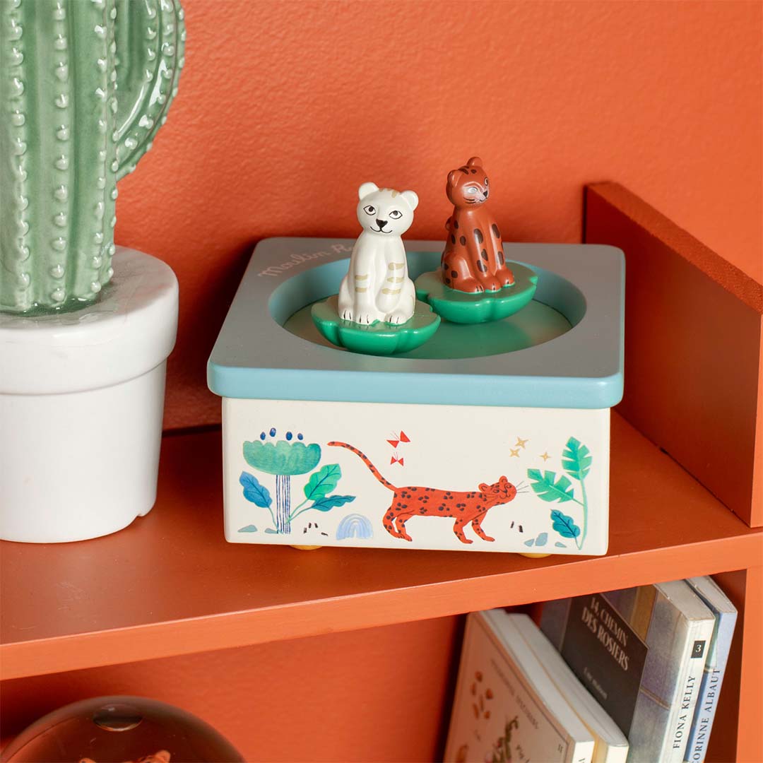 Moulin Roty houten muziekdoosje met kattenfiguren op een houten plank naast een cactus.
