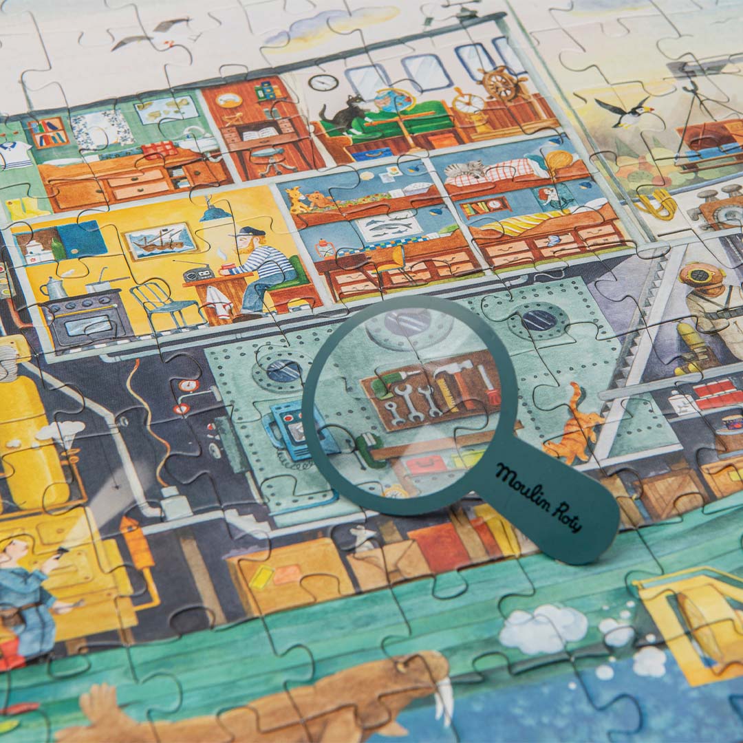 Detail van de Moulin Roty puzzel met een vergrootglas dat een deel van de scheepsinterieur met gereedschap uitvergroot.
