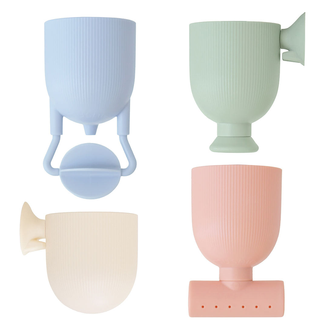Vier mushie badspeeltjes pour and play in pastelkleuren met verschillende gietfuncties, schuin afgebeeld.