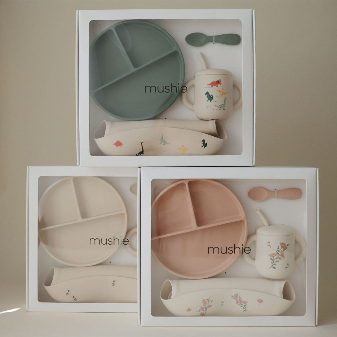 Drie Mushie siliconen voedingssets voor baby's in geschenkverpakkingen, met dino- en bloemenpatronen.