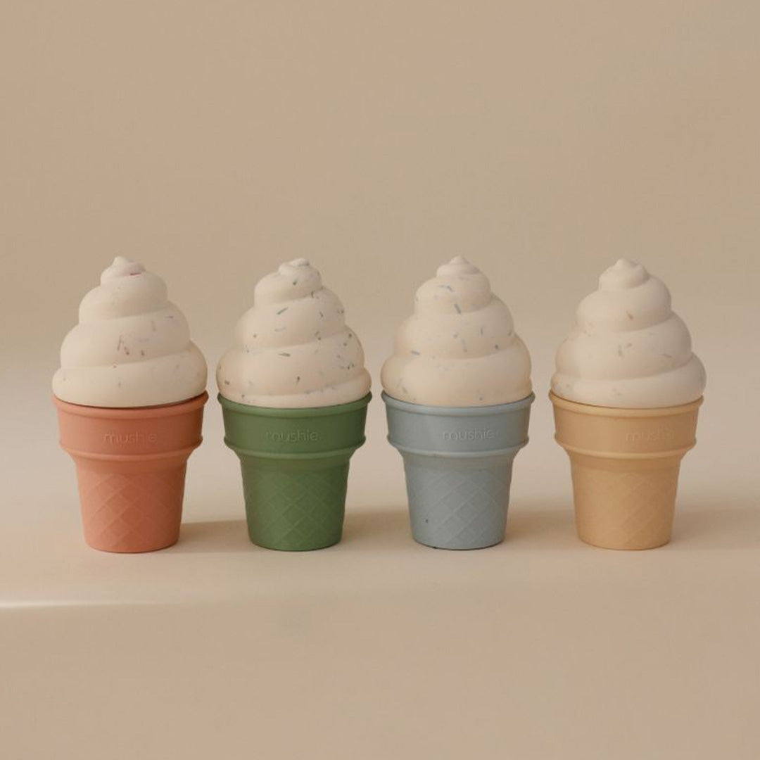Vier mushie siliconen ijsjes speelgoed in pastelkleuren op een beige ondergrond.