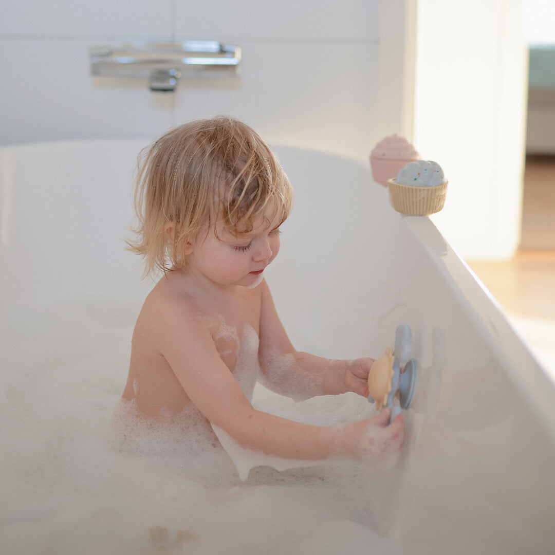 Peuter speelt in een bubbelbad met de mushie zon- en wolken spinner met zuignap.