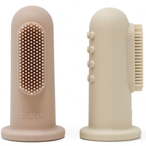 Twee Mushie siliconen babytandenborstels in sand en blush staan naast elkaar.