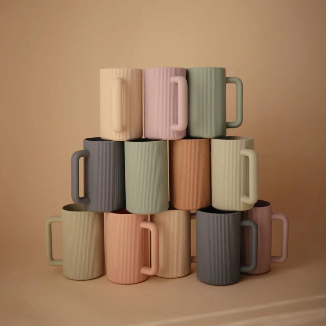 Een stapel mushie badspoelbekers in verschillende pastelkleuren.