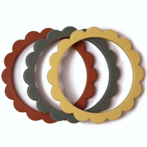 Drie mushie bijtring armbanden in de kleuren clay, dried thyme en sunshine liggen over elkaar heen.