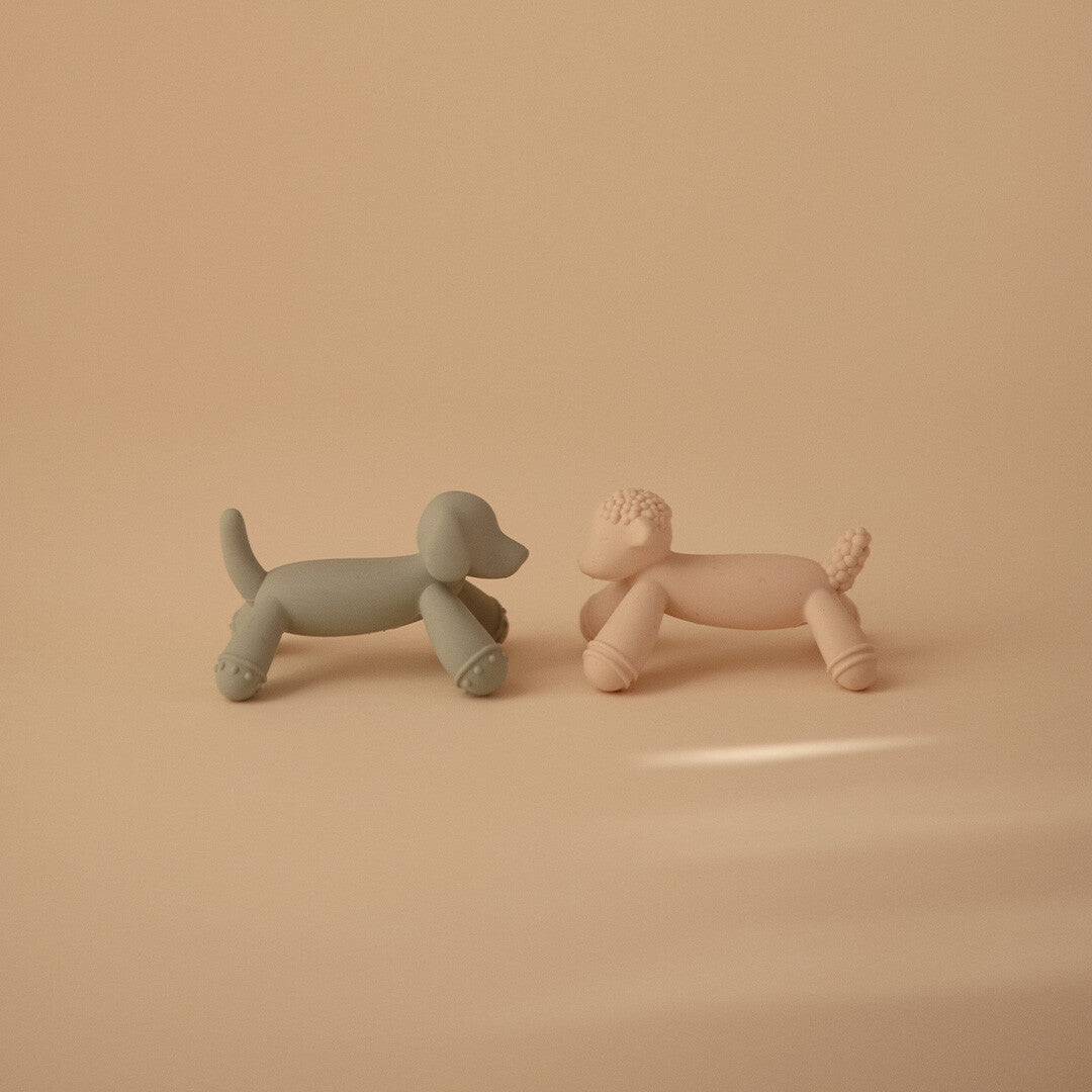Twee mushie bijtspeeltjes, een beige lammetje en een grijs hondje, staan naast elkaar.