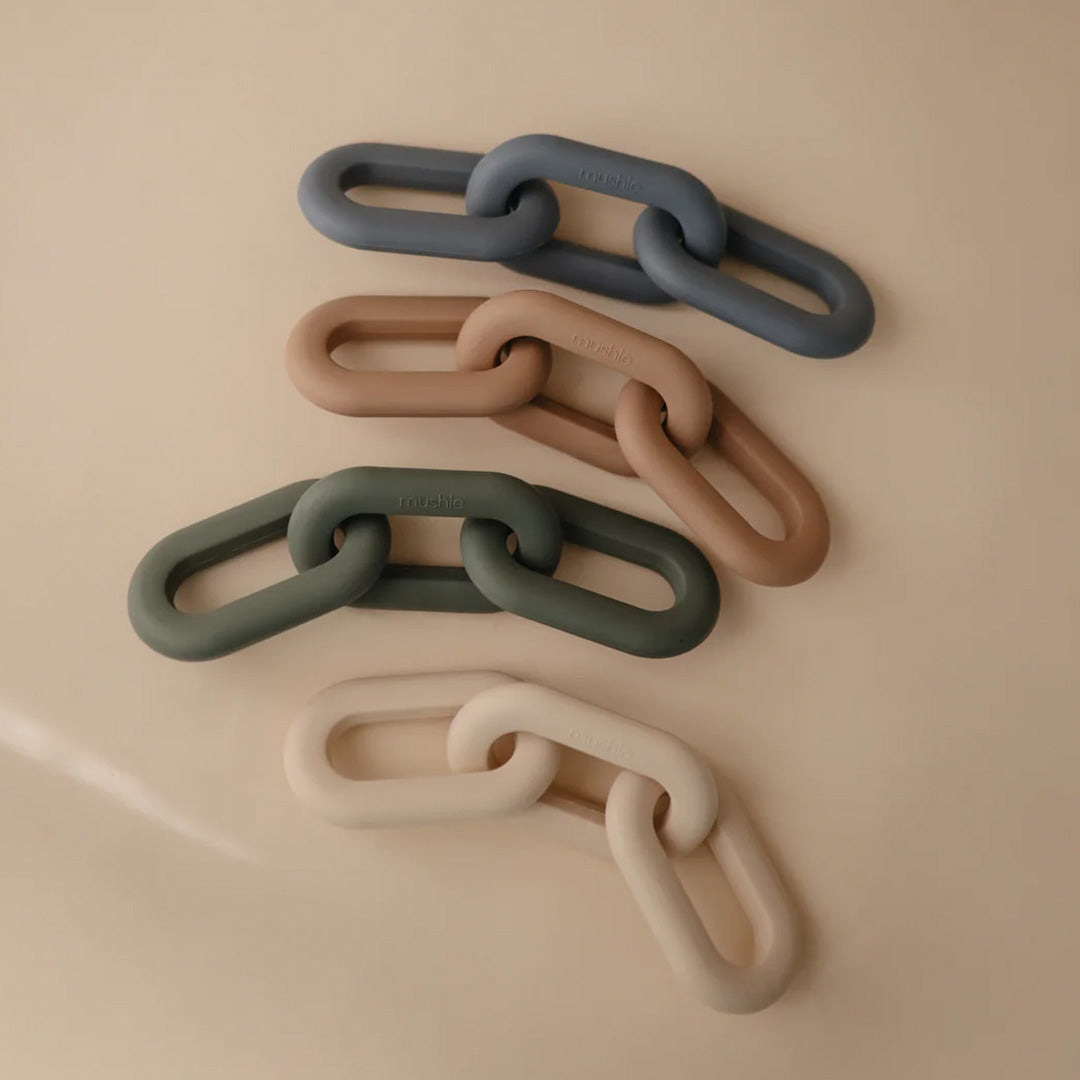 Vier mushie bijtspeelgoed sets met siliconen schakels in verschillende kleuren.