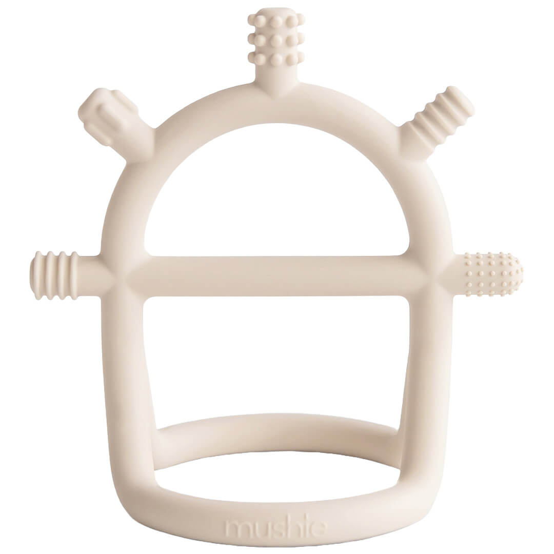 Mushie beige siliconen bijtspeelgoed met handvat en getextureerde oppervlakken.