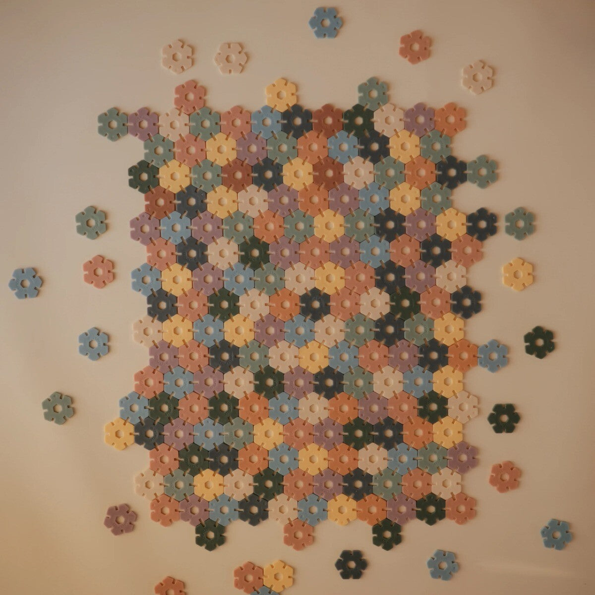 Een groot rechthoekig patroon van in elkaar geklikte mushie bouwblokken in diverse pastelkleuren.