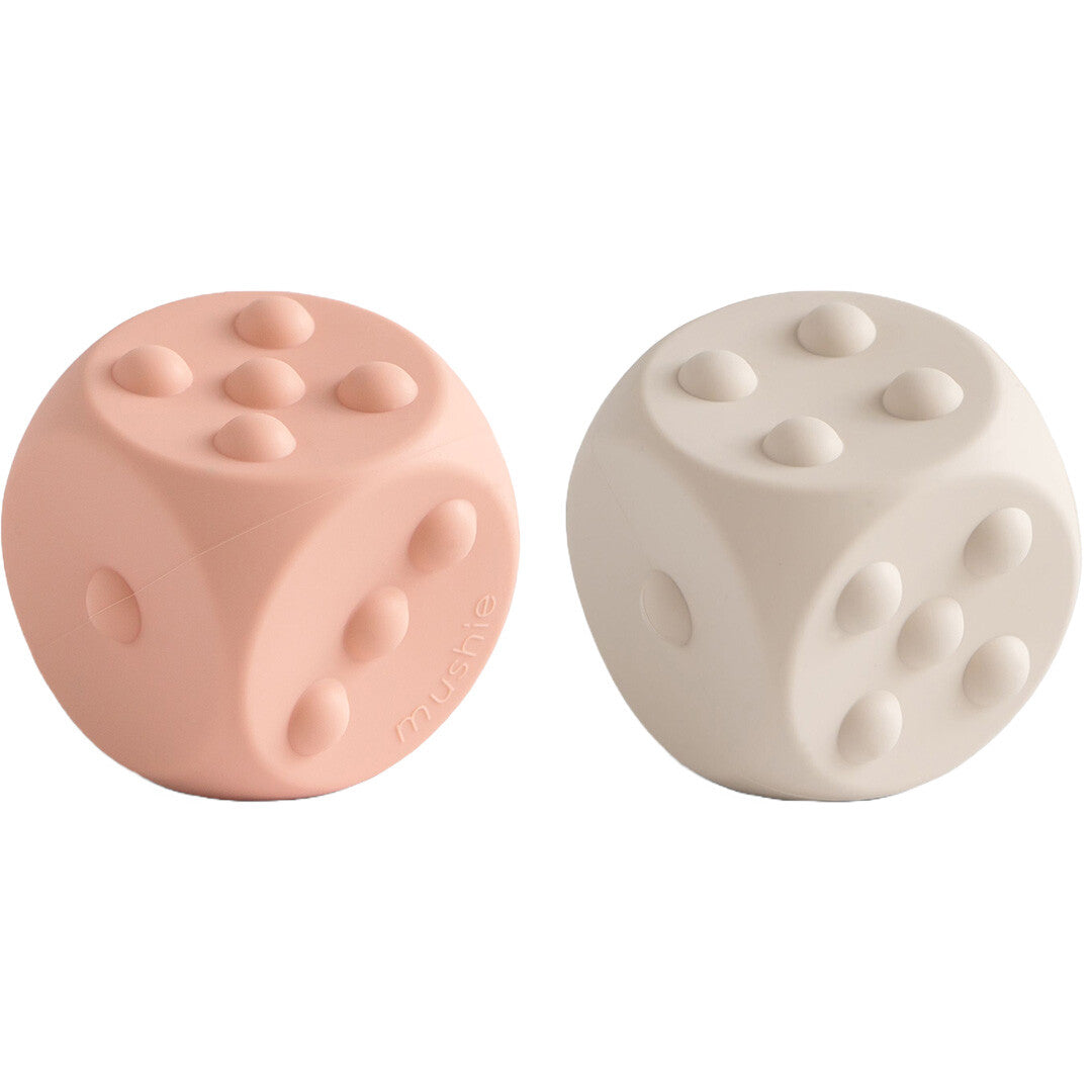 Twee mushie siliconen sensorische dobbelstenen, één in blush roze en één in lichtbeige, met voelbare stippen.