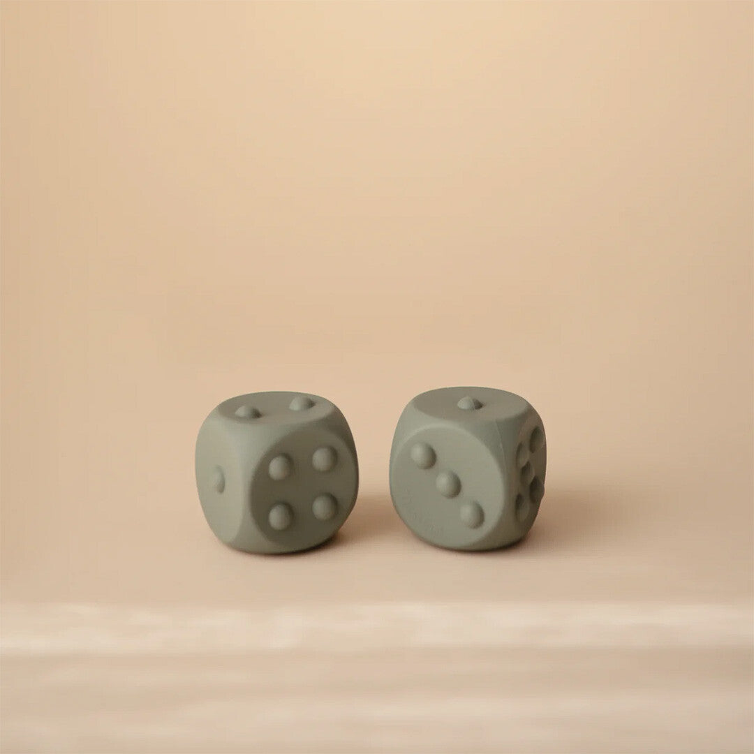 Twee mushie siliconen bijtspeelgoed dobbelstenen in gedempt groen op een beige achtergrond.