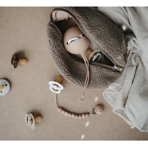 Een beige fopspeendoosje in een bruine teddy tas met fopspenen ernaast.