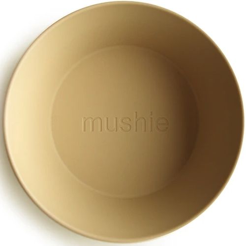 Bovenaanzicht van een mushie kinderkom in mosterdgeel met het merklogo in de bodem.