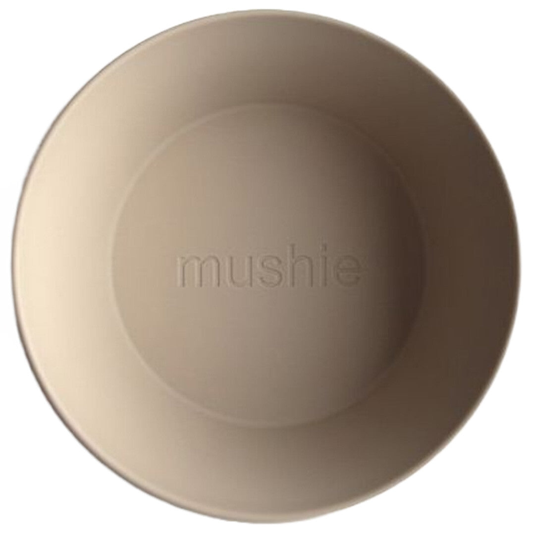 Bovenaanzicht van een Mushie beige kinderkom met het merklogo in de bodem.